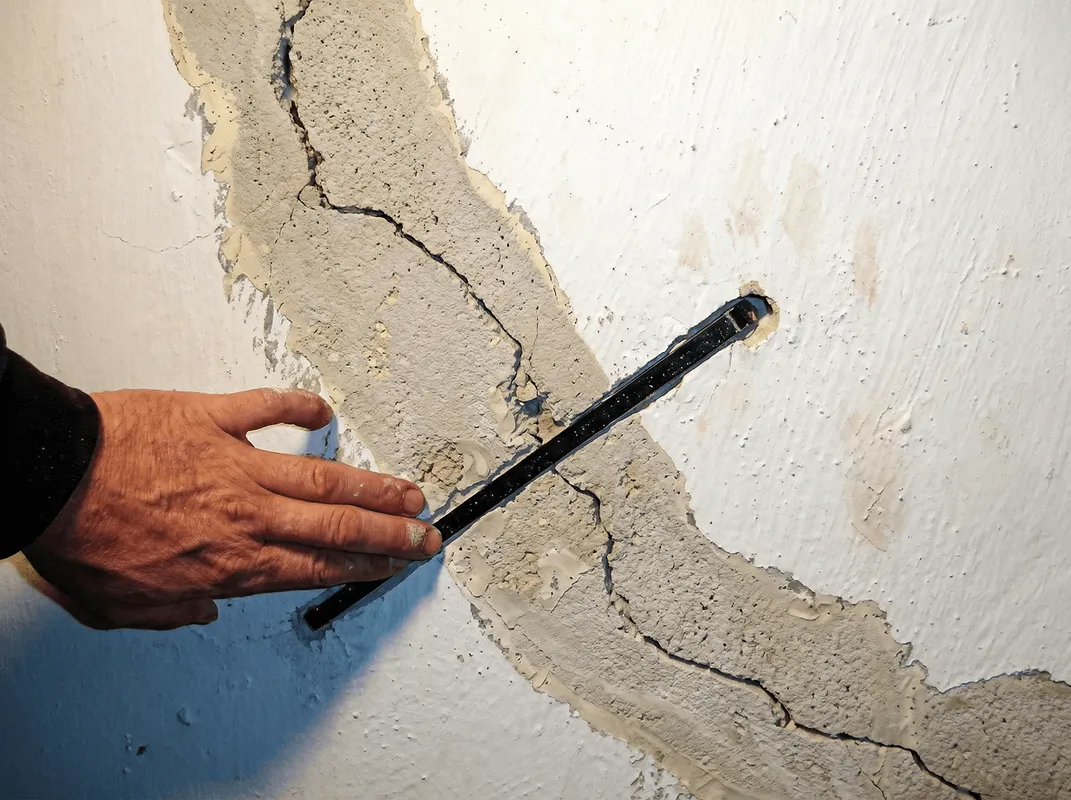 A wall with a large crack is being inspected by a professional in Memphis, TN